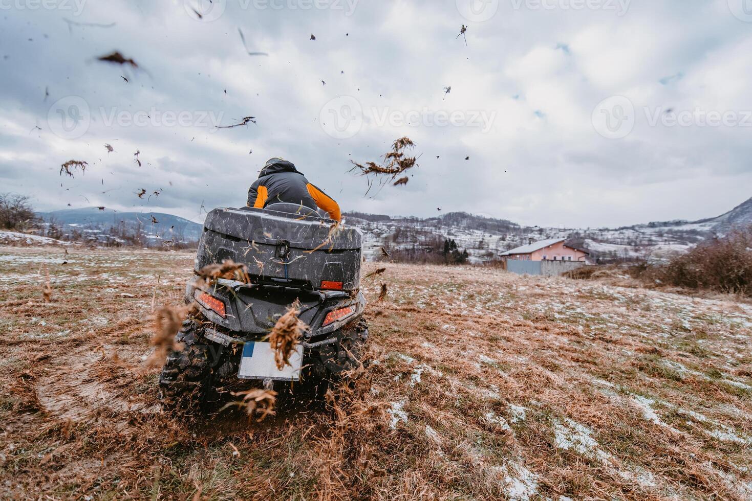 A man is fearlessly enjoying an adventurous ride on an ATV Quad through hazardous snowy terrain, embracing the thrill and excitement of the challenging mountainous landscape photo