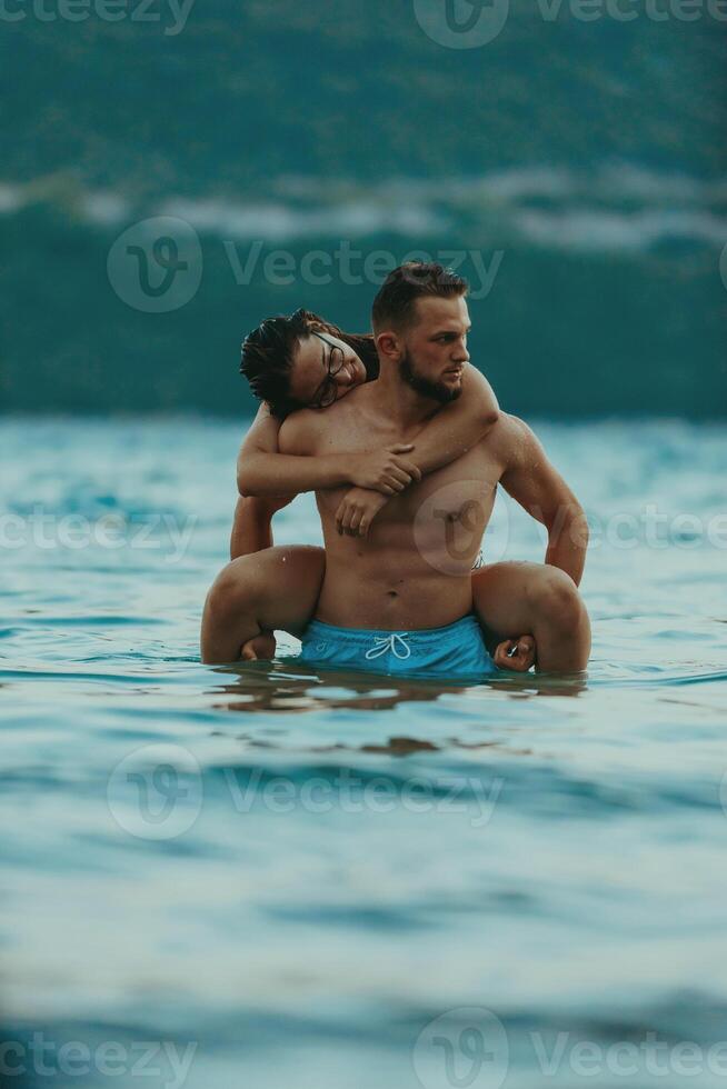 A romantic young couple sharing a passionate kiss amidst the serene beauty of the ocean at sunset. photo