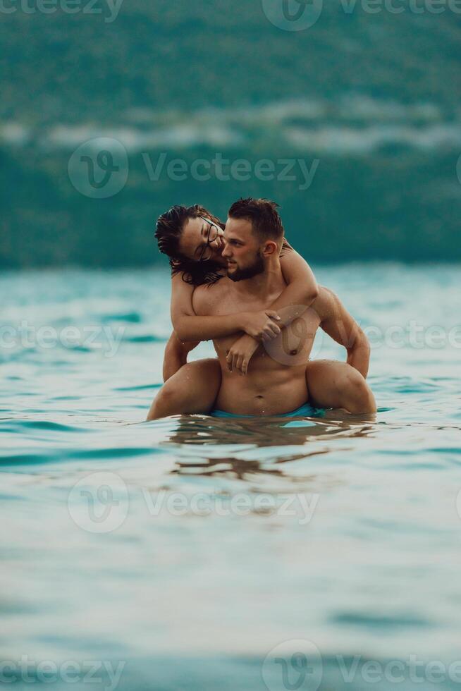 A romantic young couple sharing a passionate kiss amidst the serene beauty of the ocean at sunset. photo