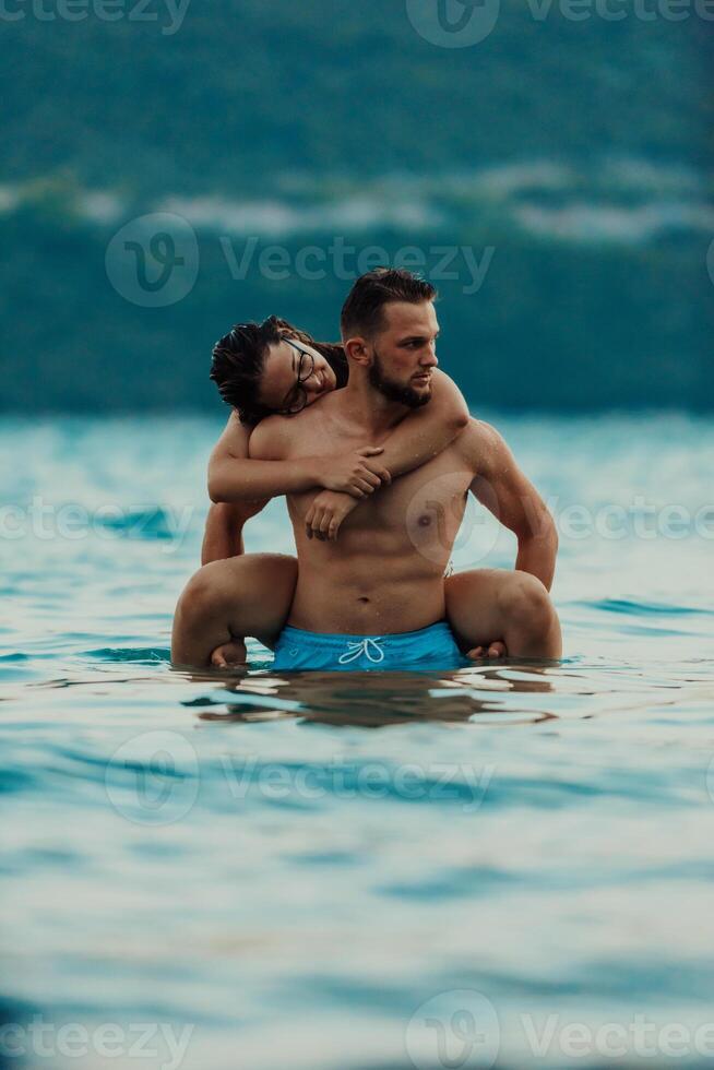 A romantic young couple sharing a passionate kiss amidst the serene beauty of the ocean at sunset. photo