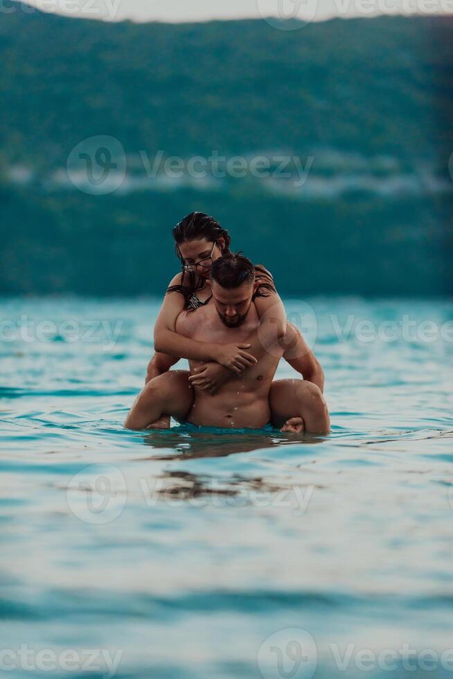 A romantic young couple sharing a passionate kiss amidst the serene beauty of the ocean at sunset. photo