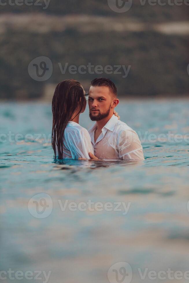 A symbolic and emotionally connected couple tenderly embraces against the backdrop of a serene sea, bathed in the warm hues of a breathtaking sunset photo