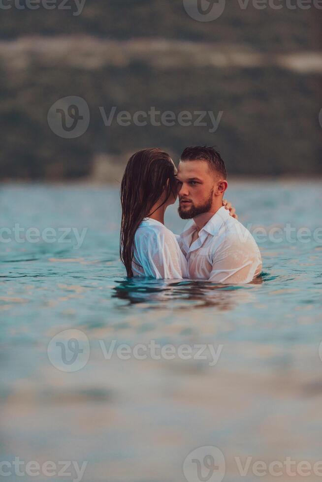 A symbolic and emotionally connected couple tenderly embraces against the backdrop of a serene sea, bathed in the warm hues of a breathtaking sunset photo