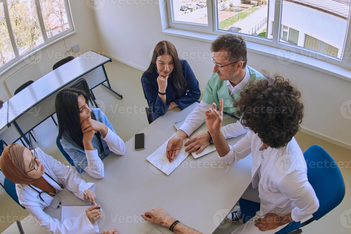 A dedicated group of doctors and medical nurses attentively listens to their colleague's work plan in a healthcare facility, fostering collaboration and ensuring high-quality patient care photo
