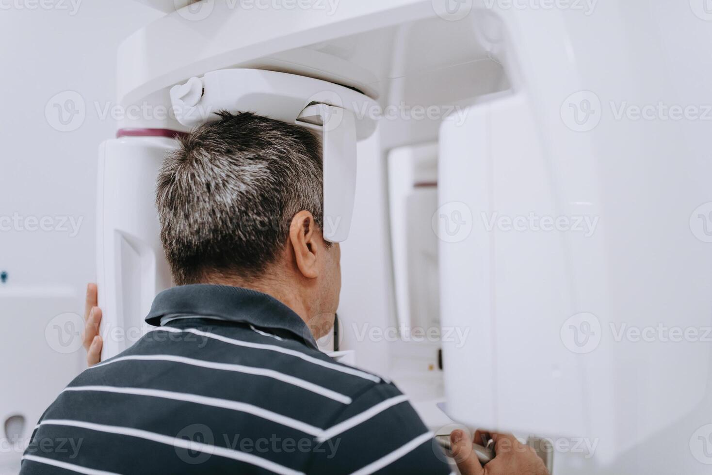 Elderly man in a modern dental clinic undergoing a 3D teeth scan for advanced diagnostics and treatment planning photo