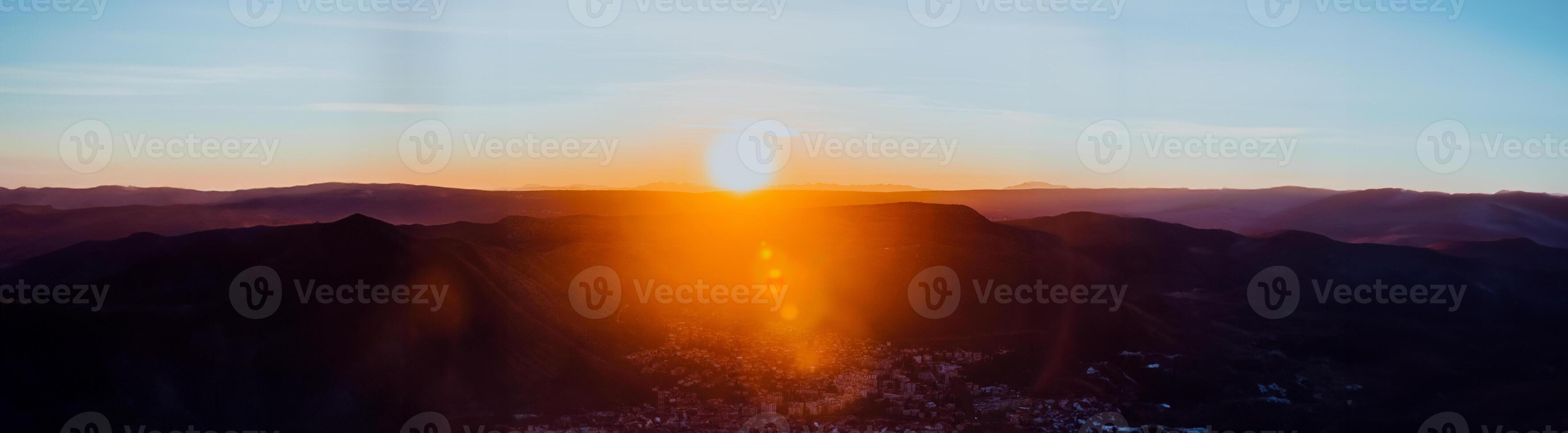 Capturing the breathtaking beauty of a vibrant orange and purple sunset over a majestic mountain during a serene summer evening photo