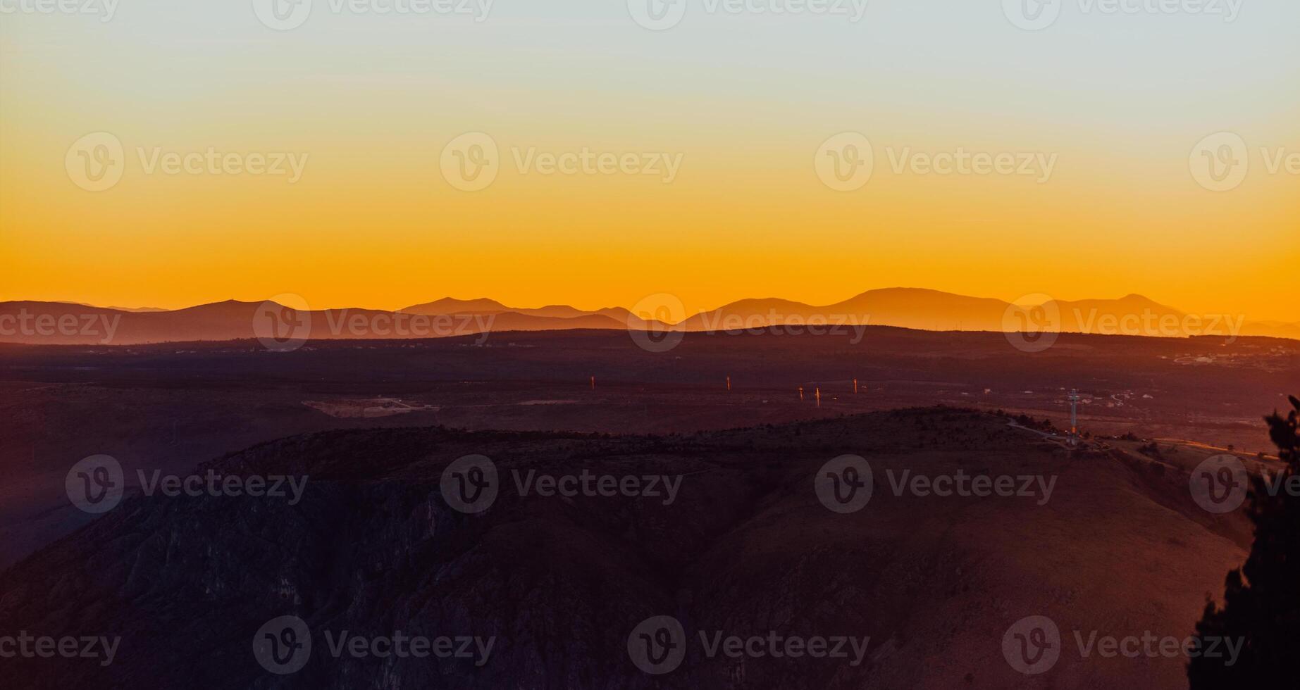 Capturing the breathtaking beauty of a vibrant orange and purple sunset over a majestic mountain during a serene summer evening photo