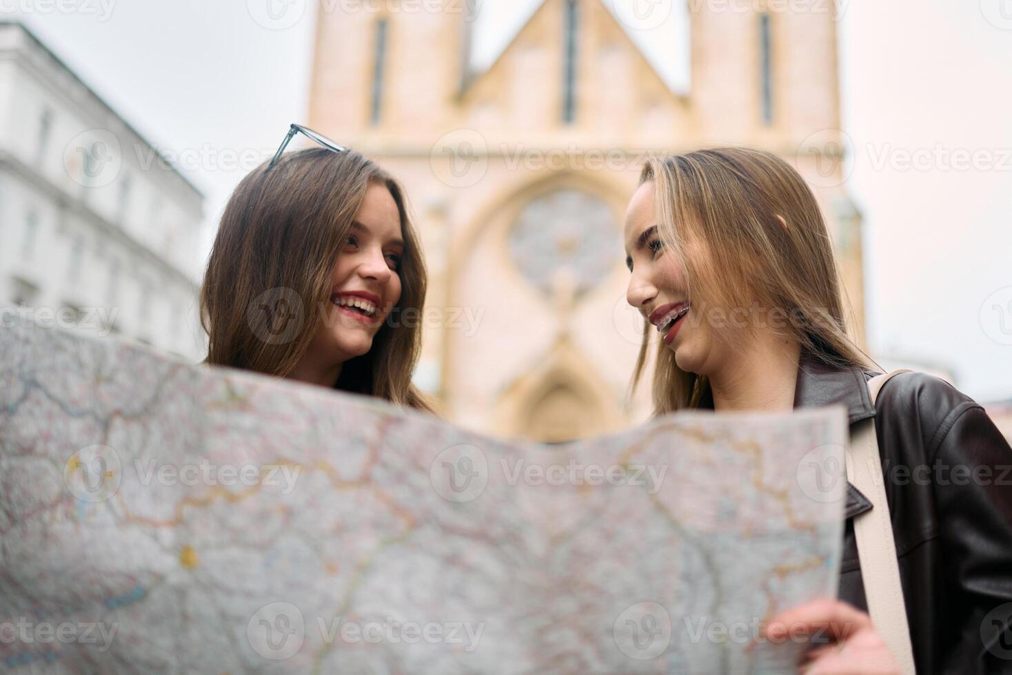 Two female tourists engage in lively discussion, surrounded by their luggage, as they plan their sightseeing journey through the bustling city streets, map in hand. photo