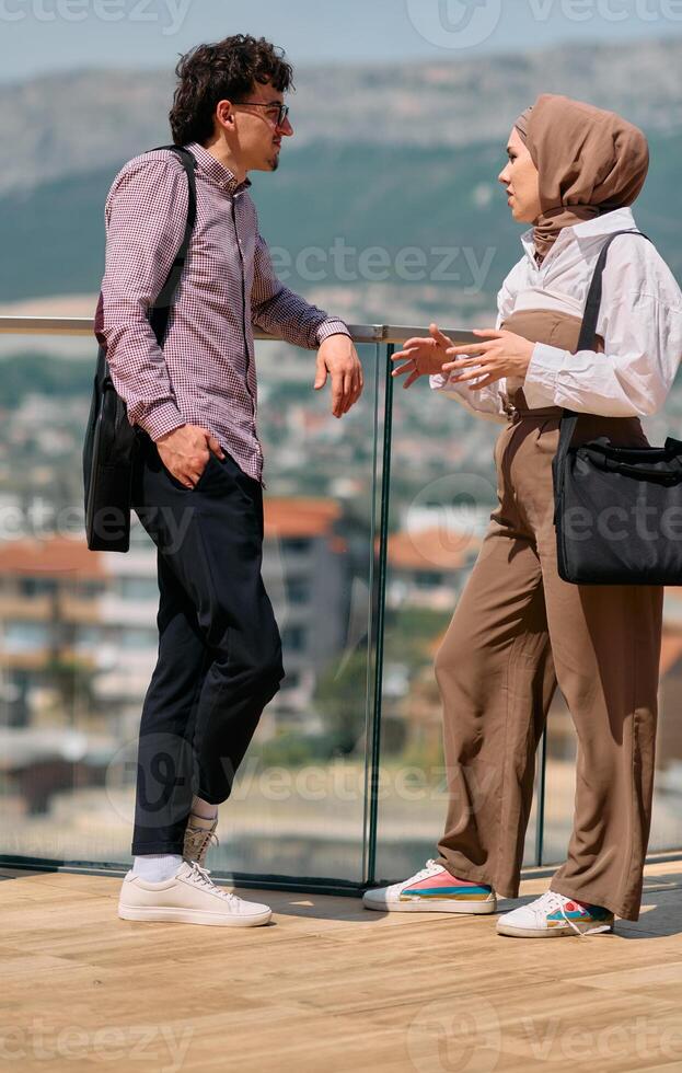 After a day at the office, a business man engages in conversation with his Muslim colleague wearing a hijab photo