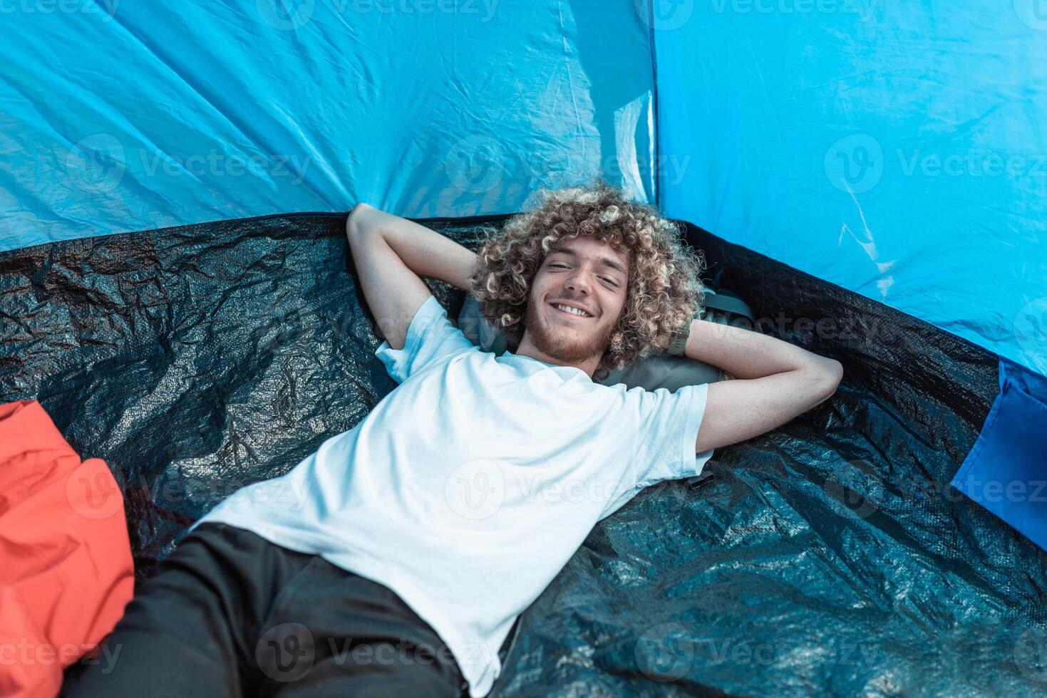 A mountaineer with an afro hairstyle li in a tent and rests from a hard hike photo
