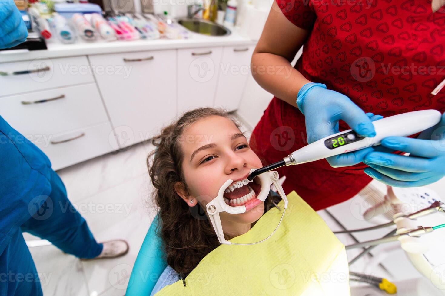 The dentist uses an ultraviolet lamp while fitting the girl with braces photo