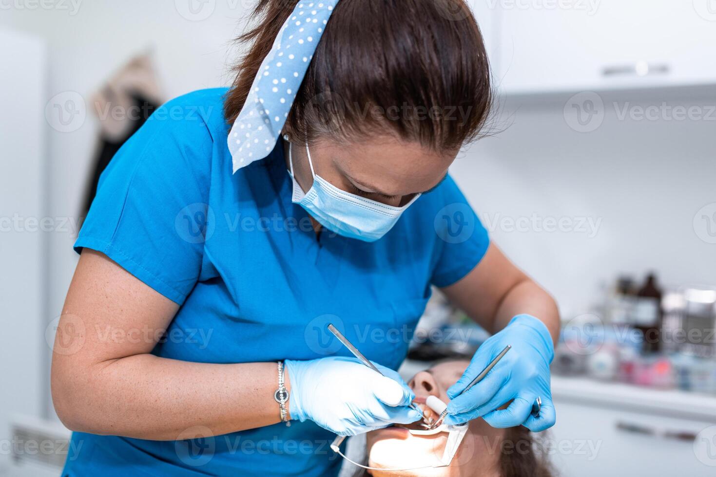 Dentist appointment at a dental clinic, placing braces locks on the teeth and pulling the archwire to fix it photo