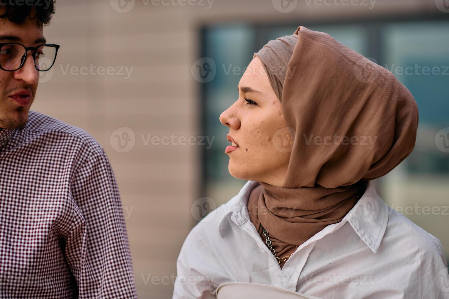 After a day at the office, a business man engages in conversation with his Muslim colleague wearing a hijab photo