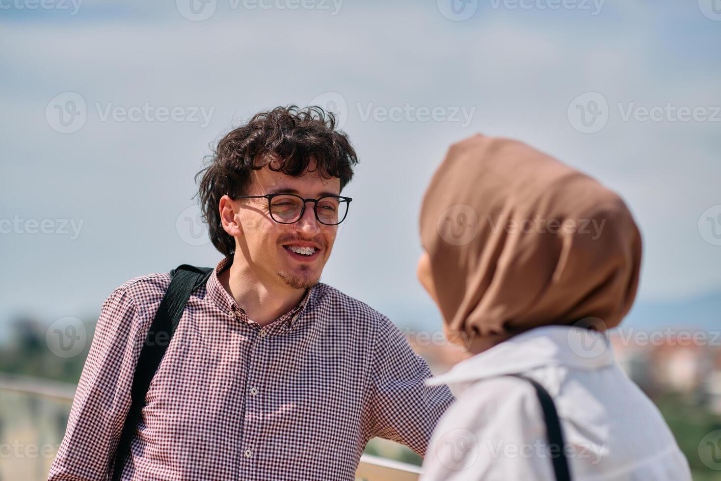 After a day at the office, a business man engages in conversation with his Muslim colleague wearing a hijab photo