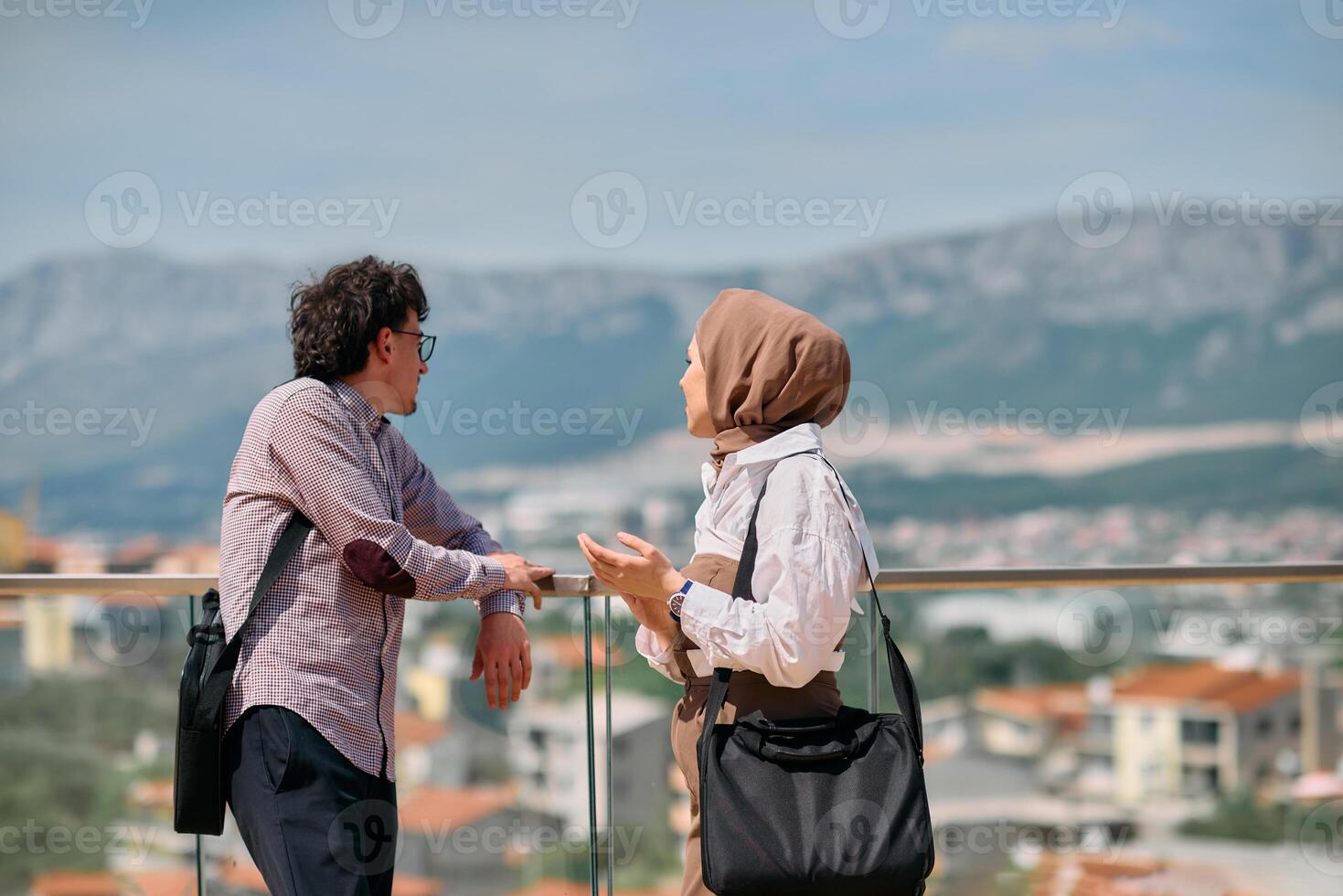 After a day at the office, a business man engages in conversation with his Muslim colleague wearing a hijab photo