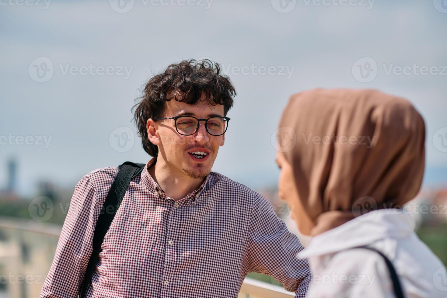 After a day at the office, a business man engages in conversation with his Muslim colleague wearing a hijab photo