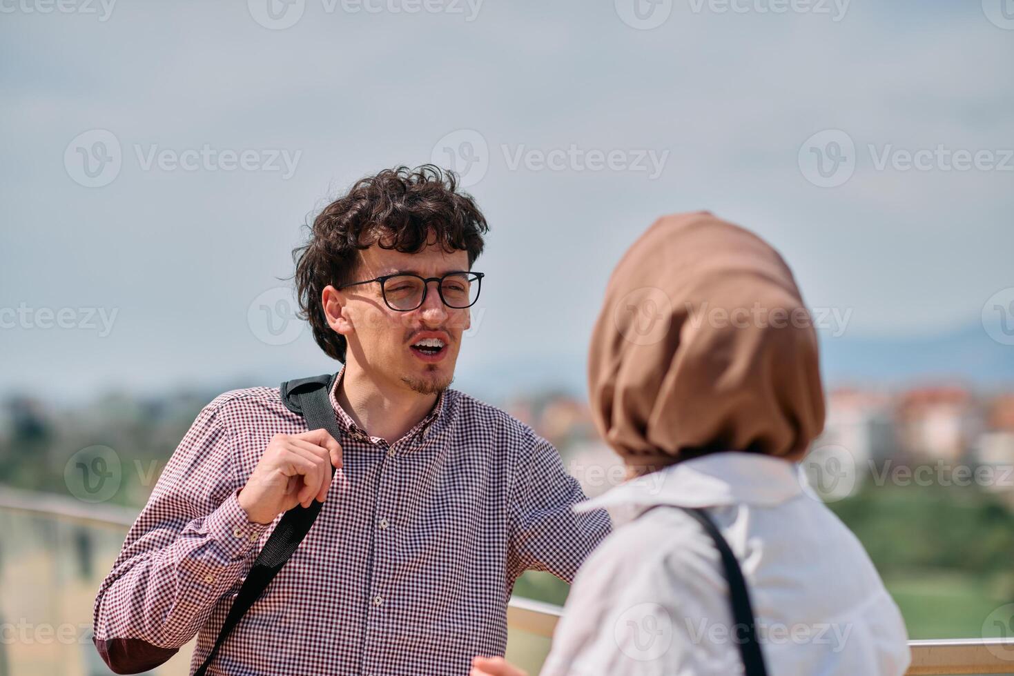 After a day at the office, a business man engages in conversation with his Muslim colleague wearing a hijab photo