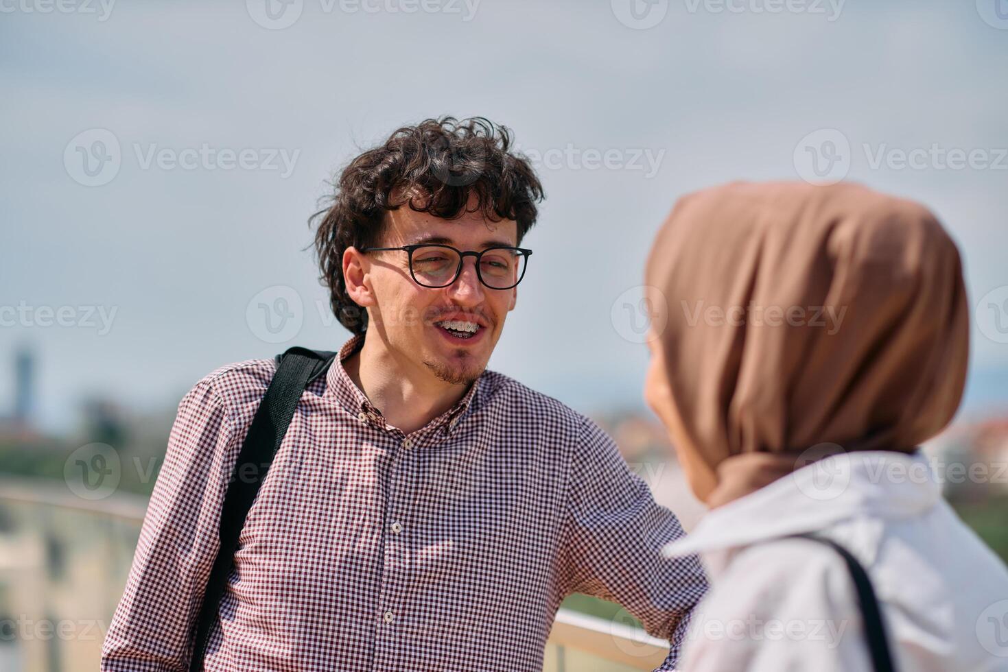 After a day at the office, a business man engages in conversation with his Muslim colleague wearing a hijab photo