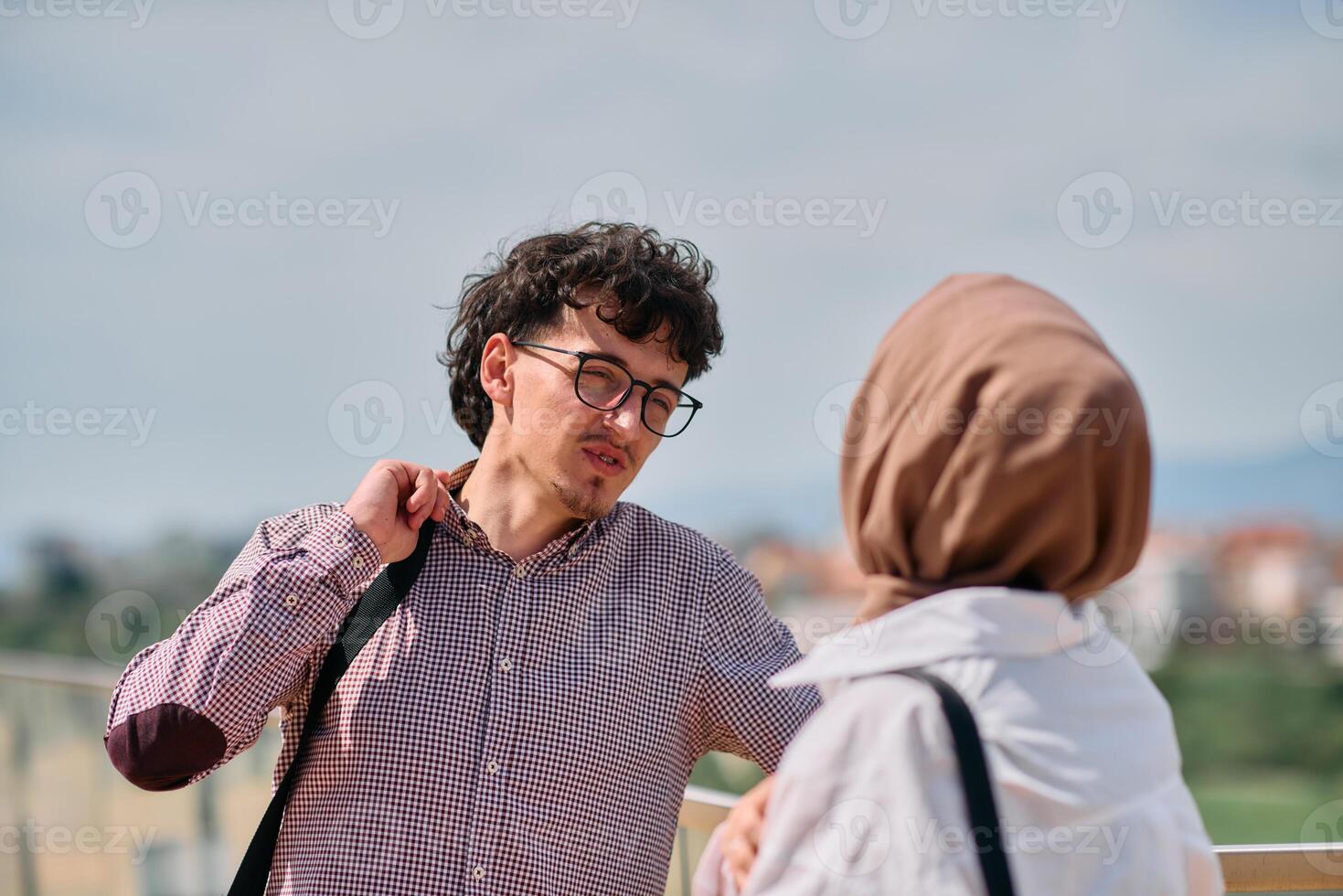 After a day at the office, a business man engages in conversation with his Muslim colleague wearing a hijab photo