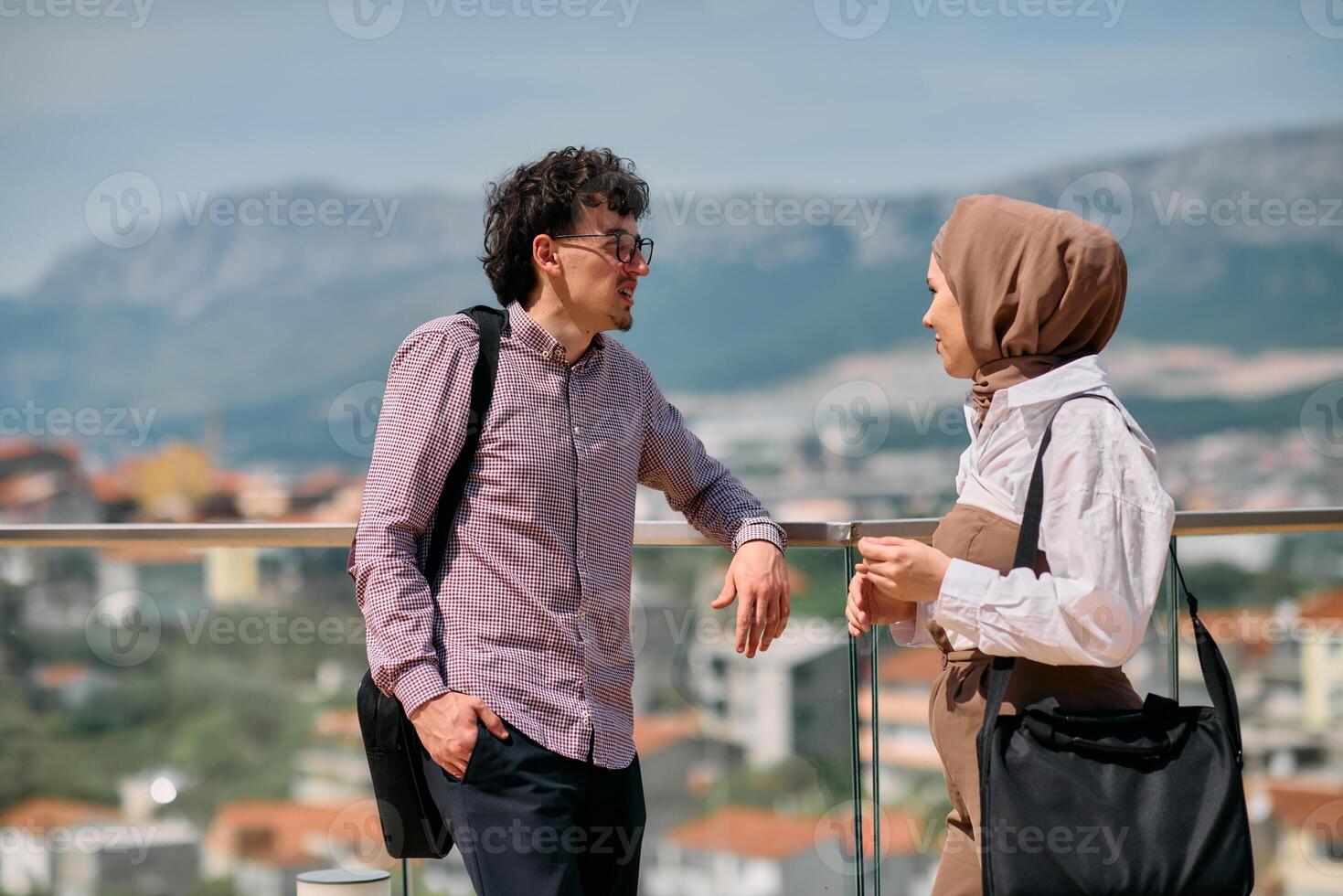 After a day at the office, a business man engages in conversation with his Muslim colleague wearing a hijab photo