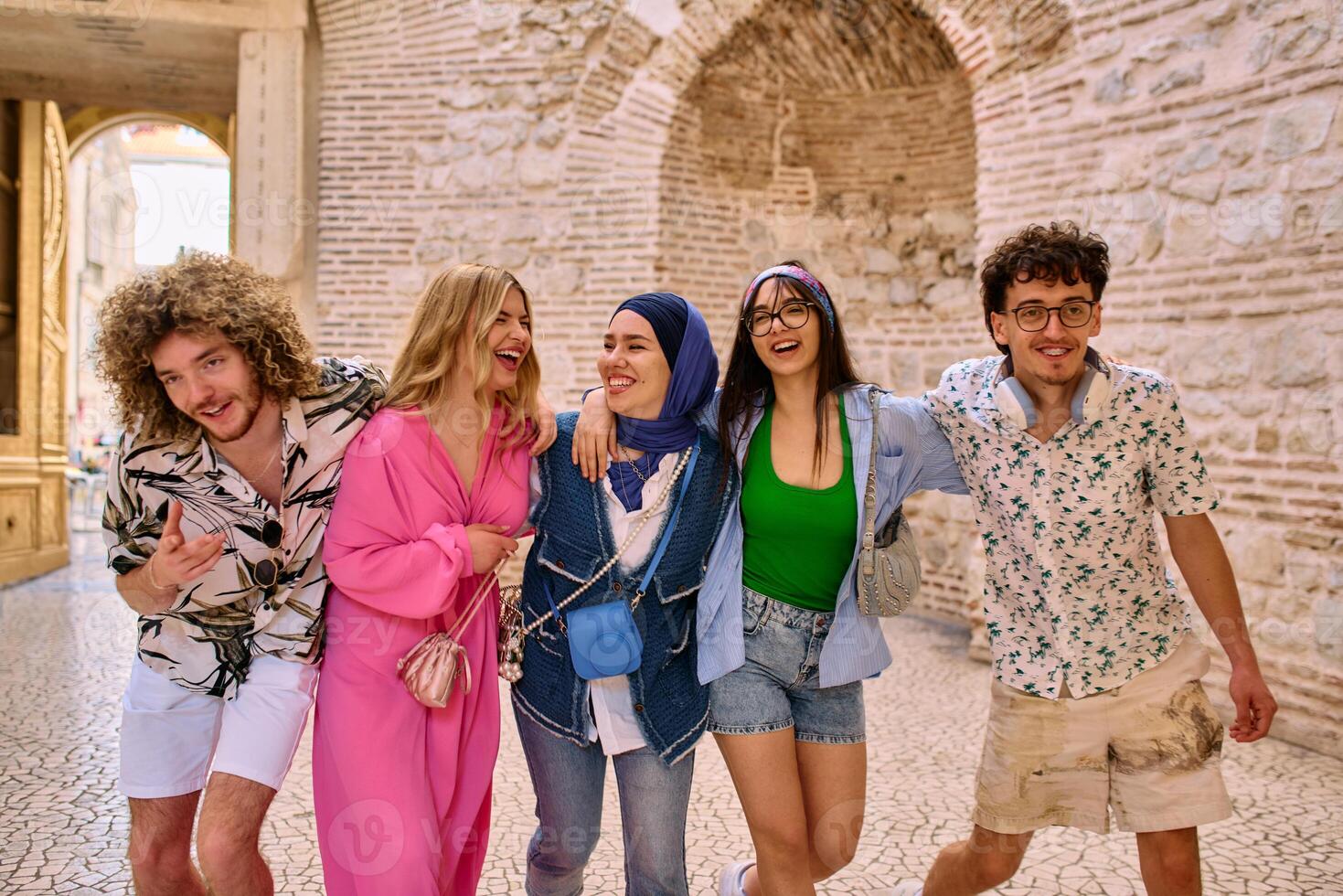 A diverse group of tourists, dressed in summer attire, strolls through the tourist city with wide smiles, enjoying their sightseeing adventure photo