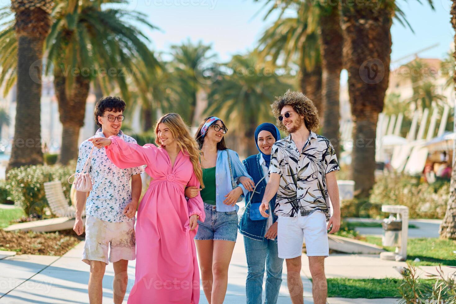 A diverse group of tourists, dressed in summer attire, strolls through the tourist city with wide smiles, enjoying their sightseeing adventure photo
