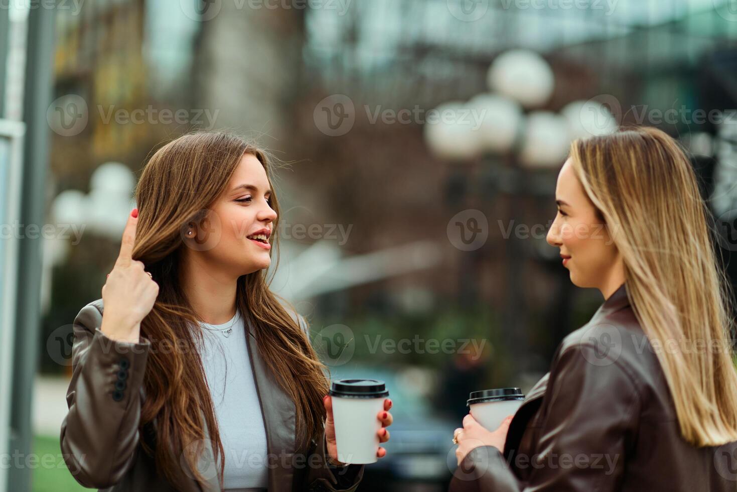 Two businesswomen enjoying a coffee break outside their office. photo
