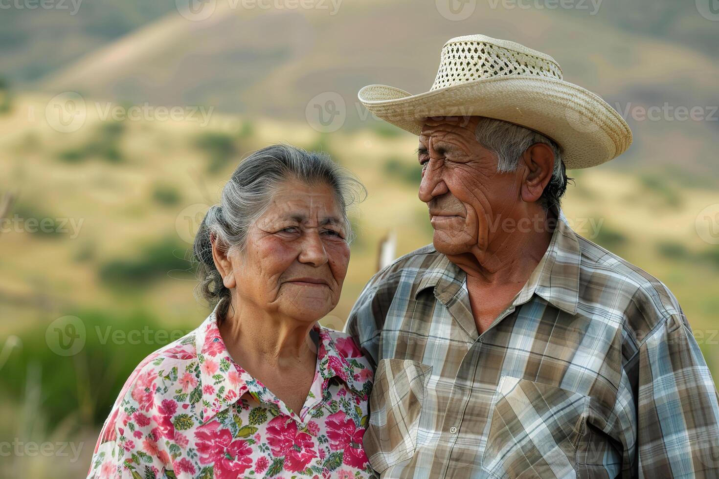 A man and woman are standing in a field, with the man wearing a straw hat photo
