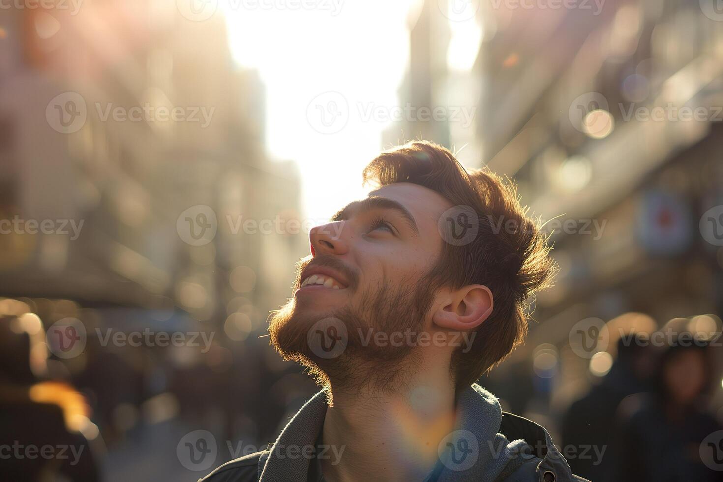A happy young caucasian man looking up at the sky alone in a busy city, sun shining photo