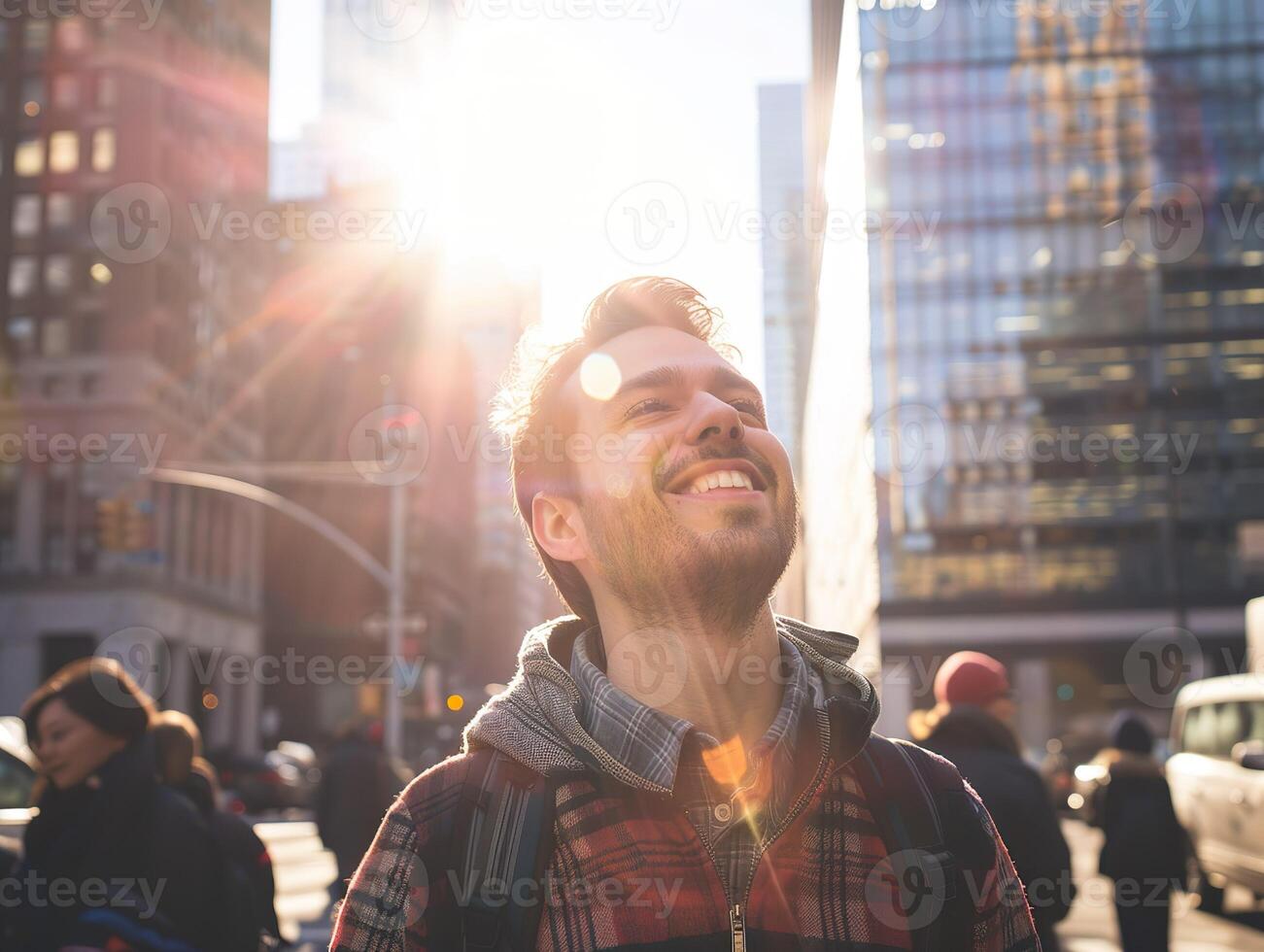 A happy young caucasian man looking up at the sky alone in a busy city, sun shining photo
