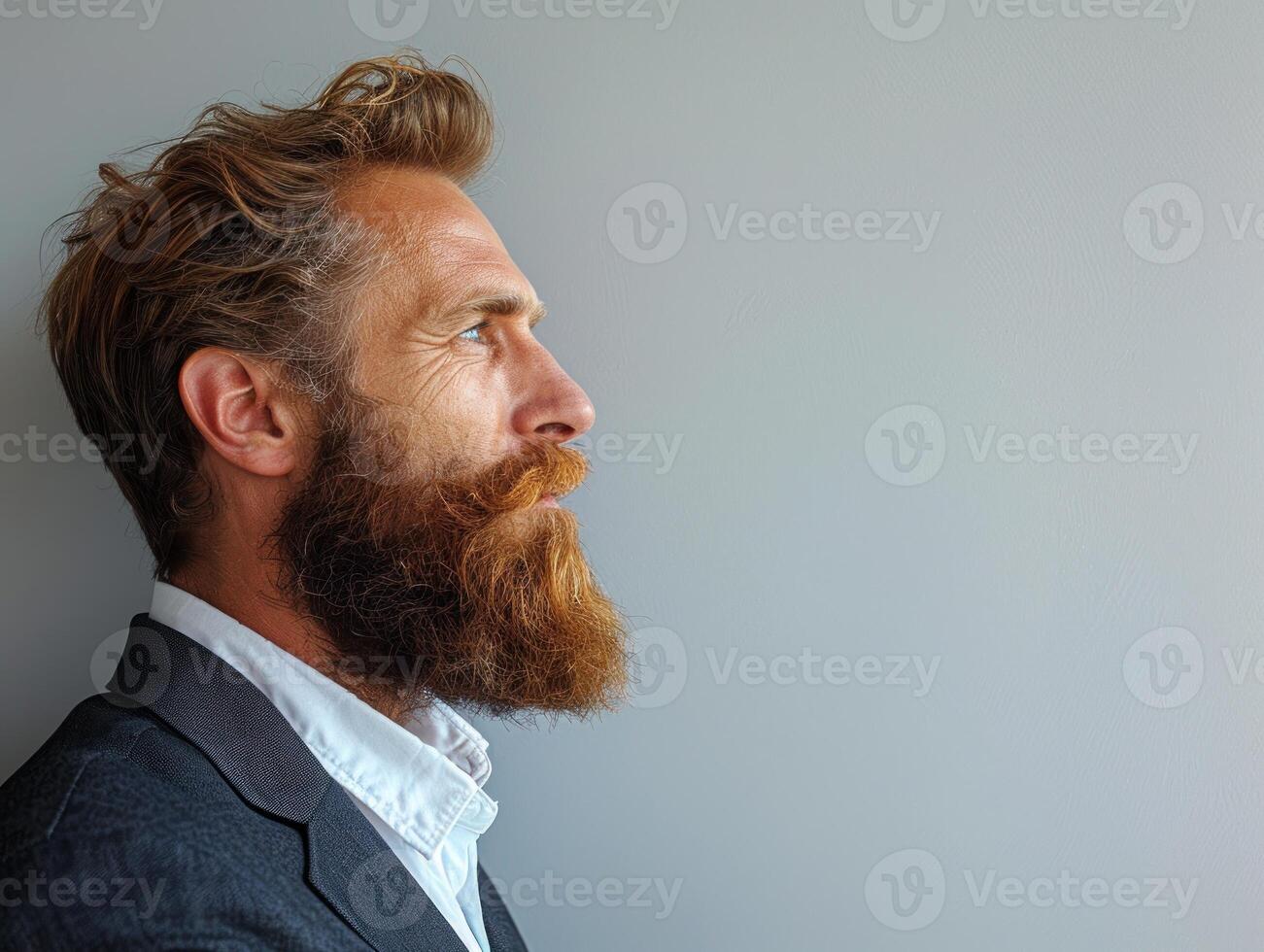 A man with a full red beard and a thoughtful expression, looking off to the side photo