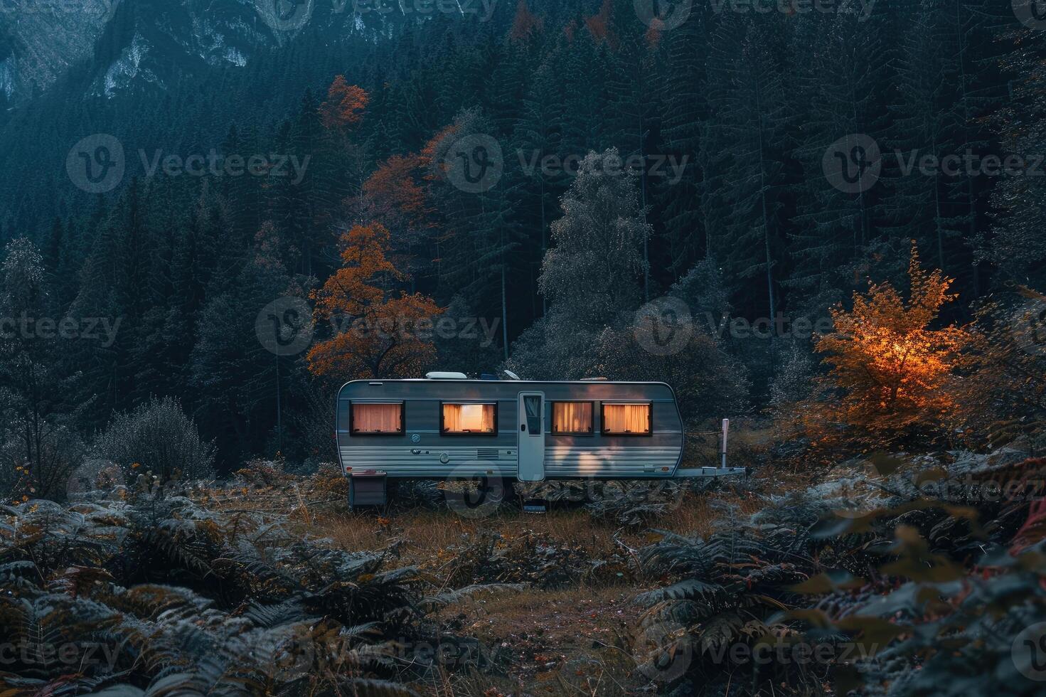 A caravan parked in a tranquil forest setting with misty mountains in the background during twilight photo
