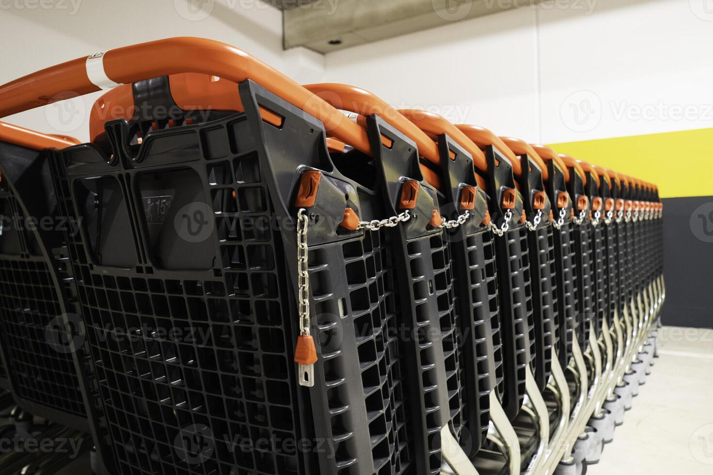 Detailed view of shopping cart handles with a focus on the red locking mechanism and chain photo