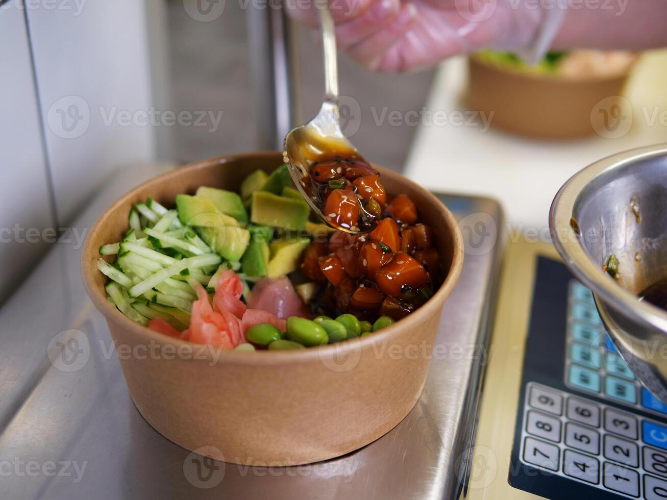 Poke with vegetables in eco dishes on scales, cook spooning fish and weighing poke. Perfect for healthy eating and culinary content fresh ingredients and balanced poke bowls for nutritious meal. photo