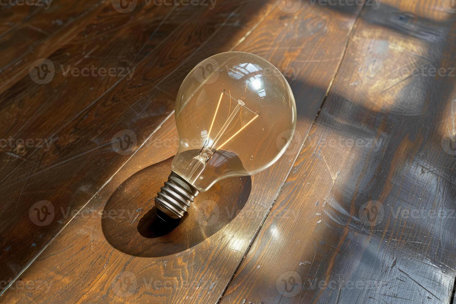 Vintage light bulb on a wooden floor with sunlight and shadows creating a warm atmosphere photo
