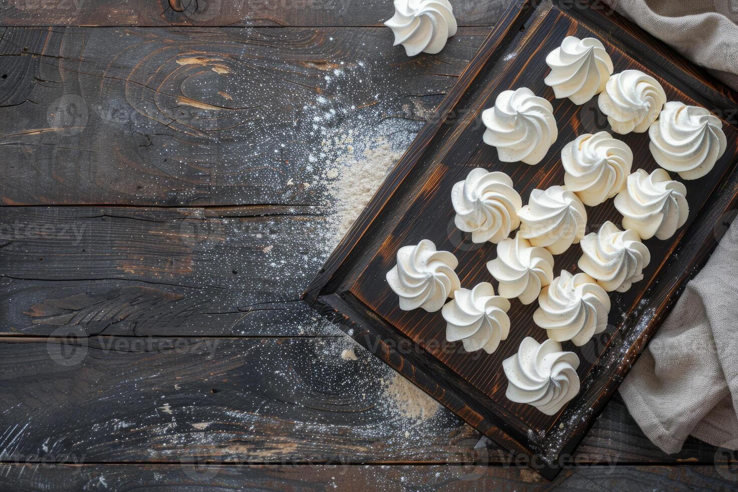 Delicate meringue cookies on a rustic wooden board, sprinkled with flour, top view photo