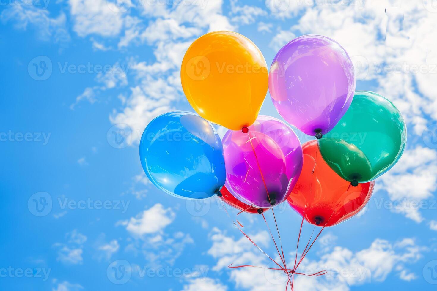 Bright colorful balloons against a blue sky with clouds photo