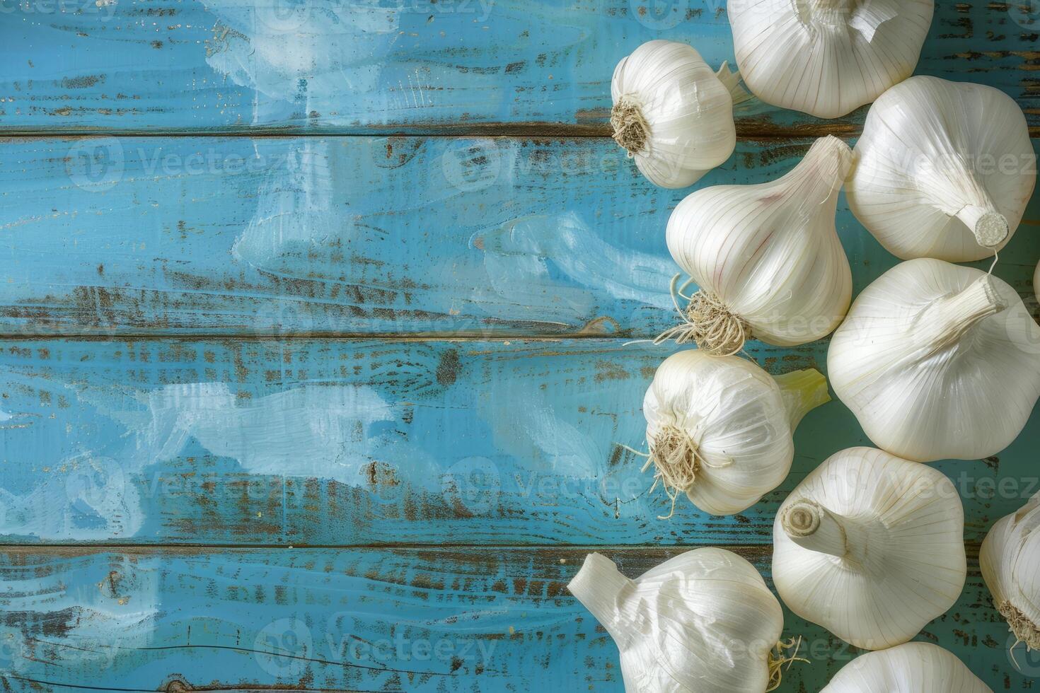 White garlic bulbs scattered on a worn blue wooden table photo