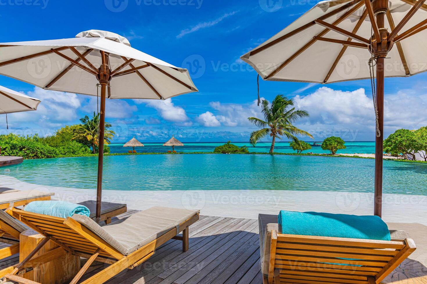 Outdoor tourism landscape. Luxury beach resort with swimming pool and beach chairs or loungers under umbrellas with palm trees and blue sky. Summer travel tourism poolside, beachfront vacation holiday photo