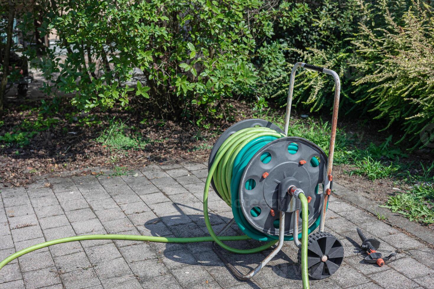 Old wheeled reel with hose pipe. Urban gardening equipment photo