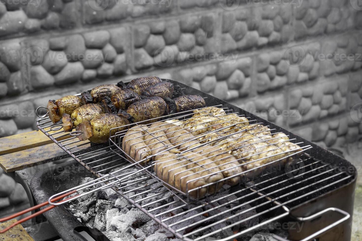 Grilled sausages and bacon with potatoes on bbq. photo