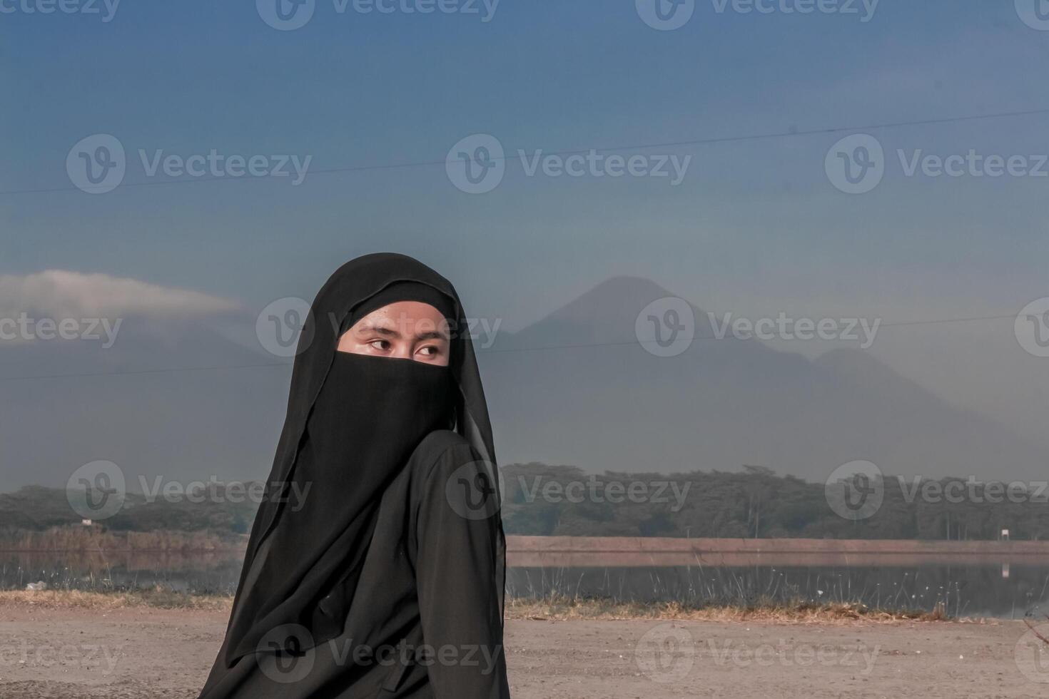 Portrait of a woman in a black veil sitting against the backdrop of tranquil mountains. photo