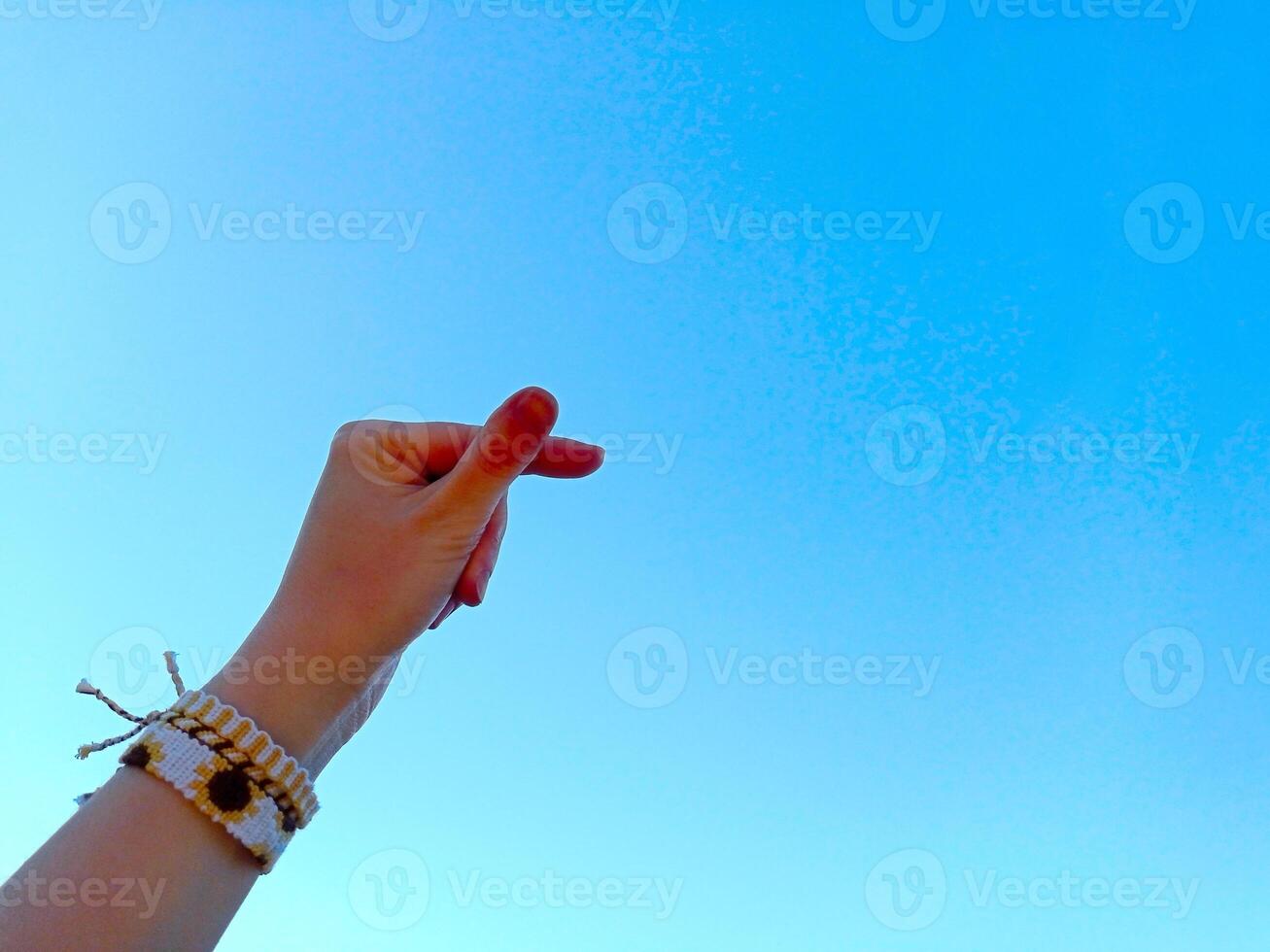 Friendship bracelets handmade of embroidery thread with knots. Female hand on blue sky background. Boho style hands jewelry accessories photo