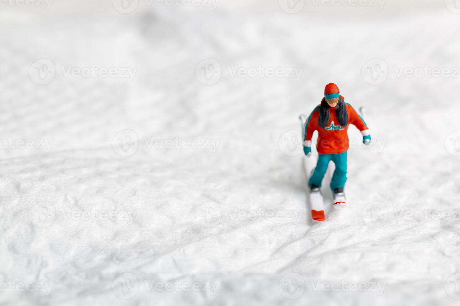 A miniature figurine of a skier dressed in vibrant winter gear. This image is perfect for themes related to winter sports photo