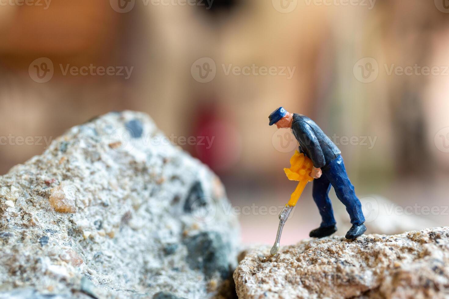 A miniature worker worker drilling a big rock . Themes of perseverance, strength and labor. photo