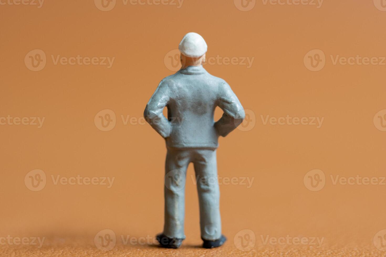 Miniature construction worker. A man dressed in a blue work uniform, complete with a hard hat. He stands confidently with his hands on his hips photo