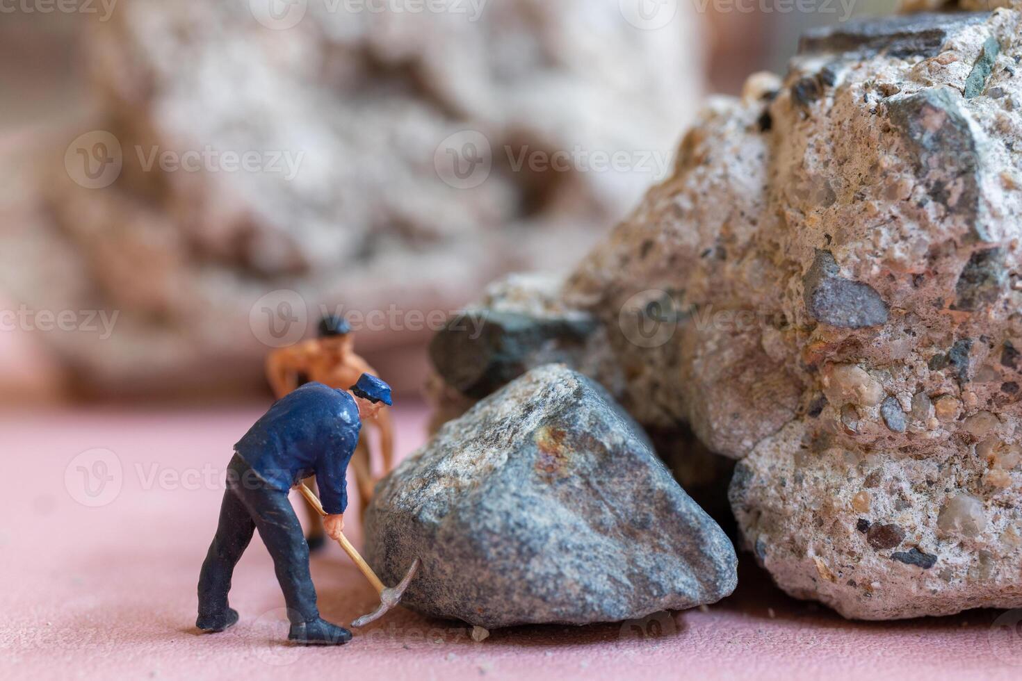 A miniature worker worker drilling a big rock . Themes of perseverance, strength and labor. photo