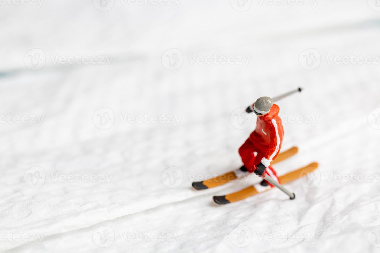 A miniature figurine of a skier dressed in vibrant winter gear. This image is perfect for themes related to winter sports photo
