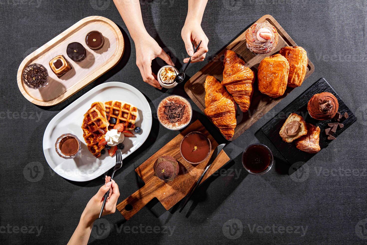 assorted cafe baked food variety Plain Croissant, chocolate pastry puff, CACAO Crispy Waffles, cacao tofu, Chocolate Puff, chocolate tart, with fork served isolated on dark background top view photo