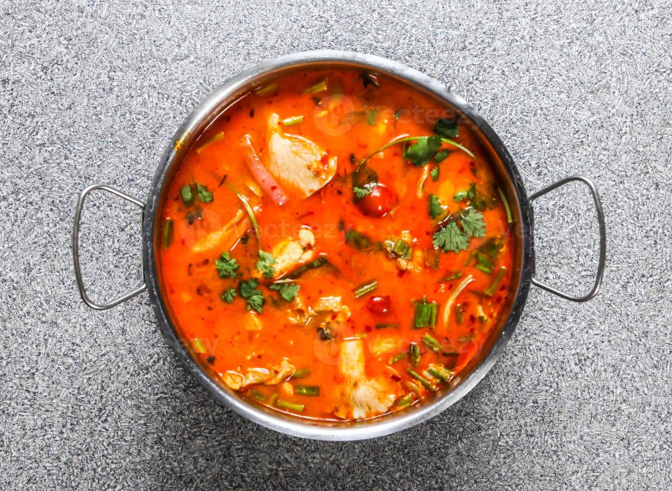 spicy tom yam soup with chicken served in broth isolated on grey background top view of hong kong fastfood photo